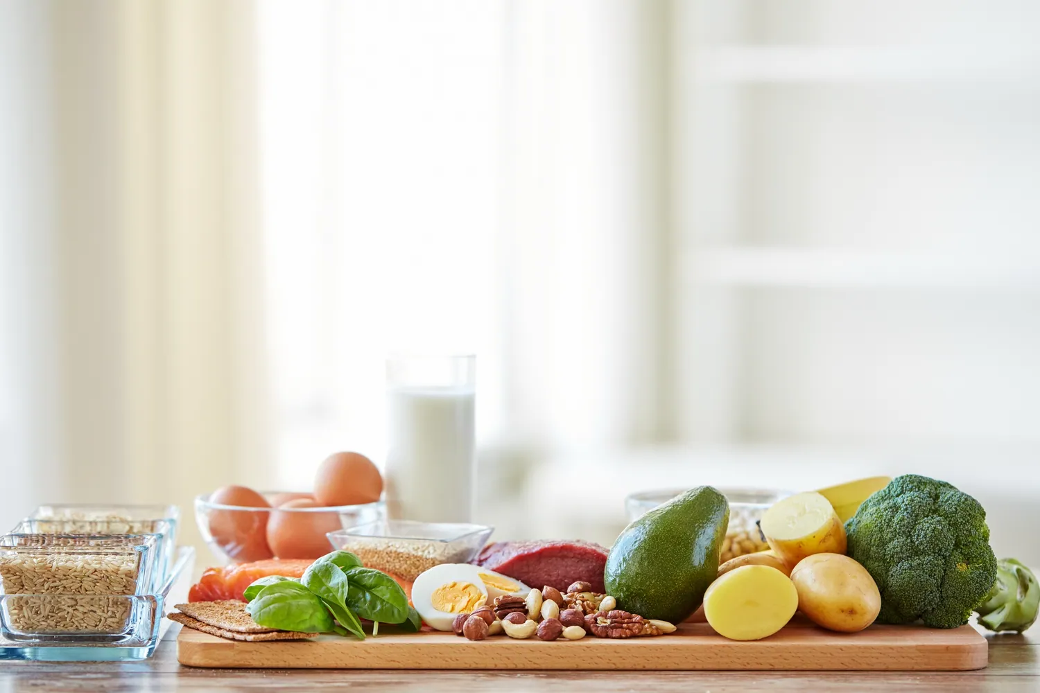 A kitchen bench laid with fresh produce, eggs and pantry staples